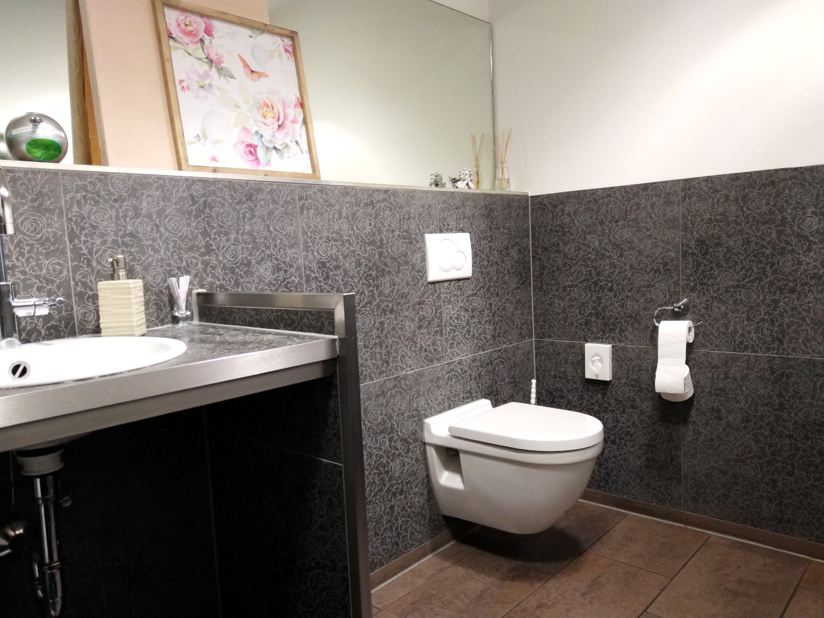 Toilette des "Alten Forstamts" mit Wand-WC und dunklen Fliesen.