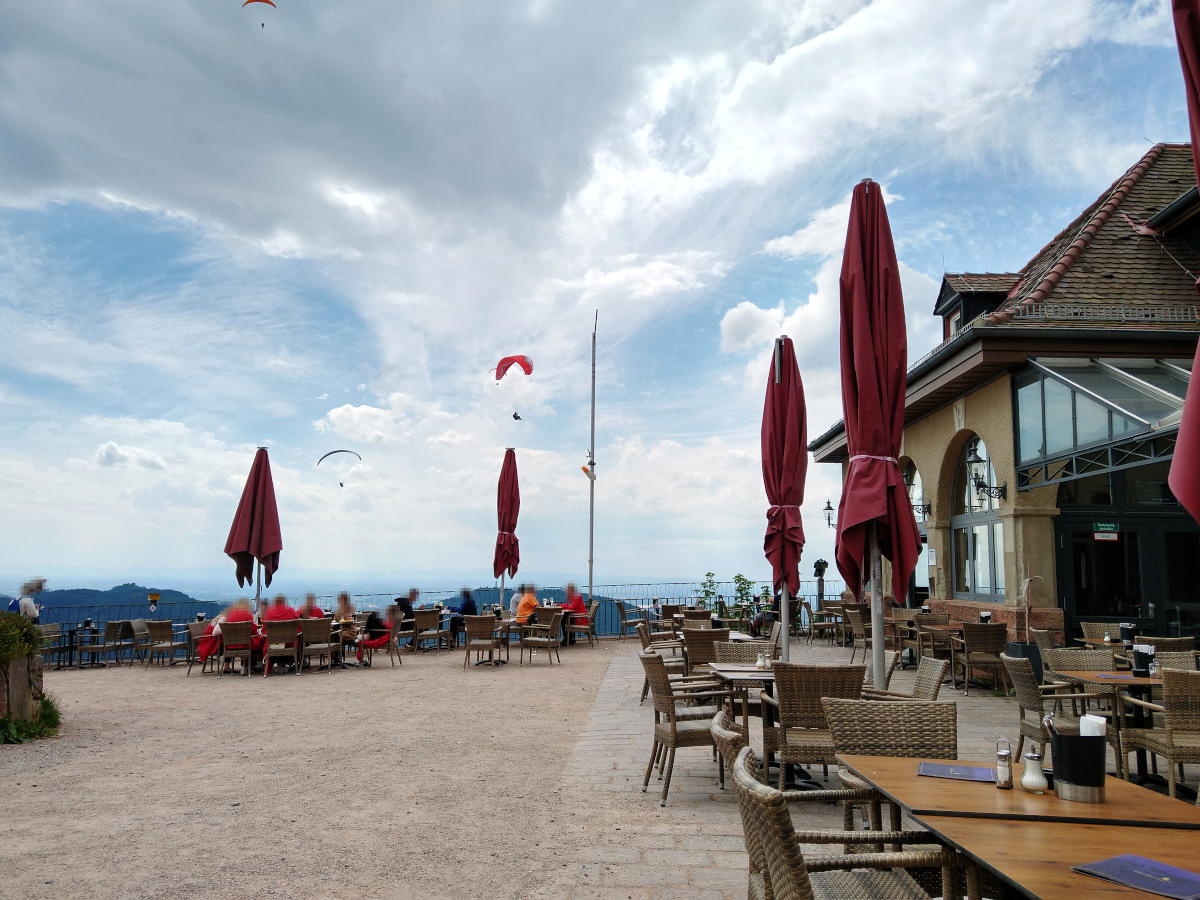 Blick von der Restaurant-Terrasse in den Himmel, wo mehrere Gleit-Schirm-Flieger zu sehen sind.