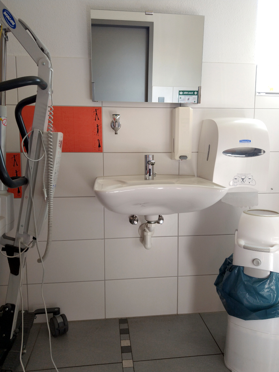 Wasch-Becken unterfahrbar. Seife und Papier-Tücher im Sitzen erreichbar. Separater Müll-Eimer.