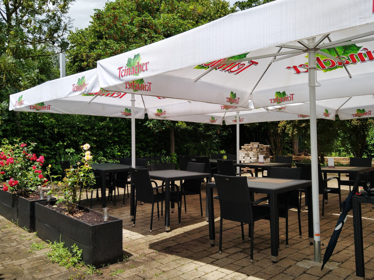 Außenbereich des Restaurants Et Can mit mehreren Tischen unter Sonnenschirmen
