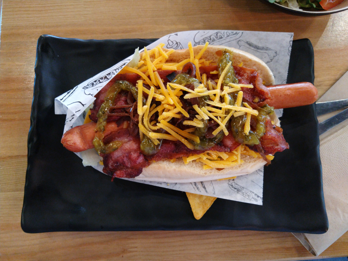 Hotdog mit Speck, Cheddar, Paprika und Soße.