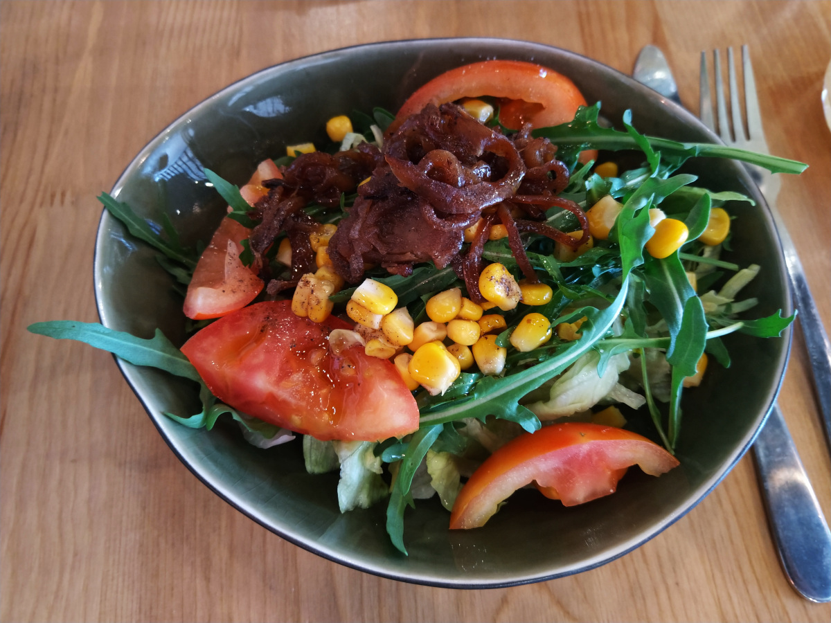 Kleine Schale mit Salat: Rucola, Mais-Körner, Tomaten und karamellisierten Zwiebeln.