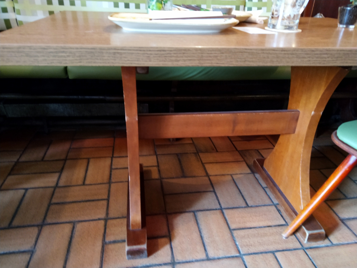 Detail-Ansicht vom Tisch. Dieser hat 2 breite Tischbeine mit einem Querbalken dazwischen.