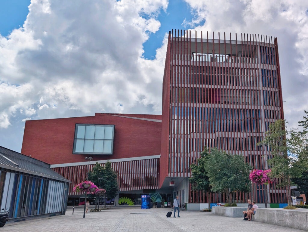 Großes, blockartiges Gebäude aus rotem Backstein, mit länglichen, vertikalen Fenstern und einem großen rechteckigen Fenster.