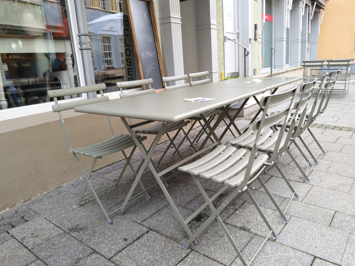 Tische mit Stühlen im Außenbereich. Tische mit Querstreben.