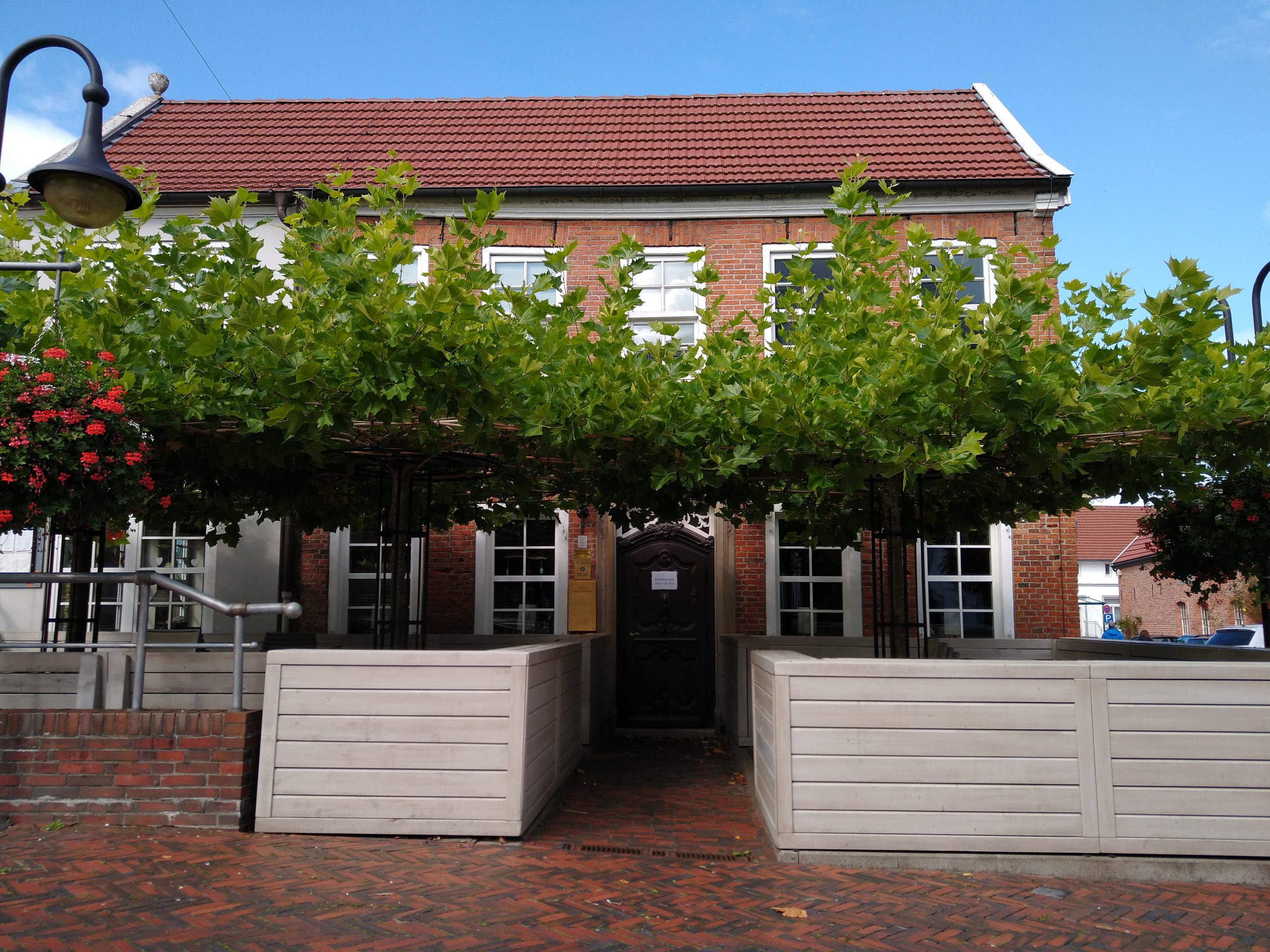 Stufenloser Eingang ins Restaurant. Links und rechts neben dem Eingang separate Lauben unter Bäumen.