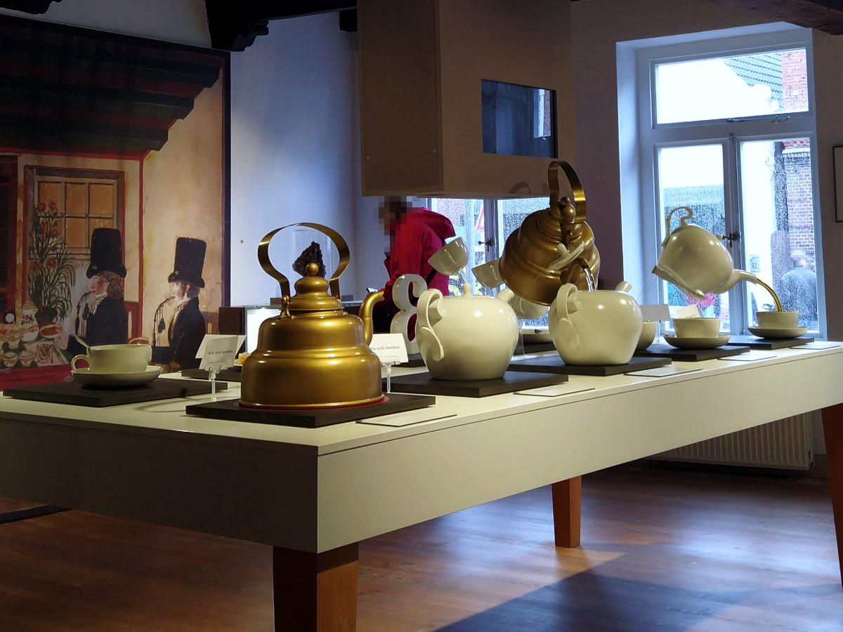 Ein Tisch, auf dem mit übergroßen Modellen die ostfriesische Tee-Zeremonie schritt-weise dargestellt ist.