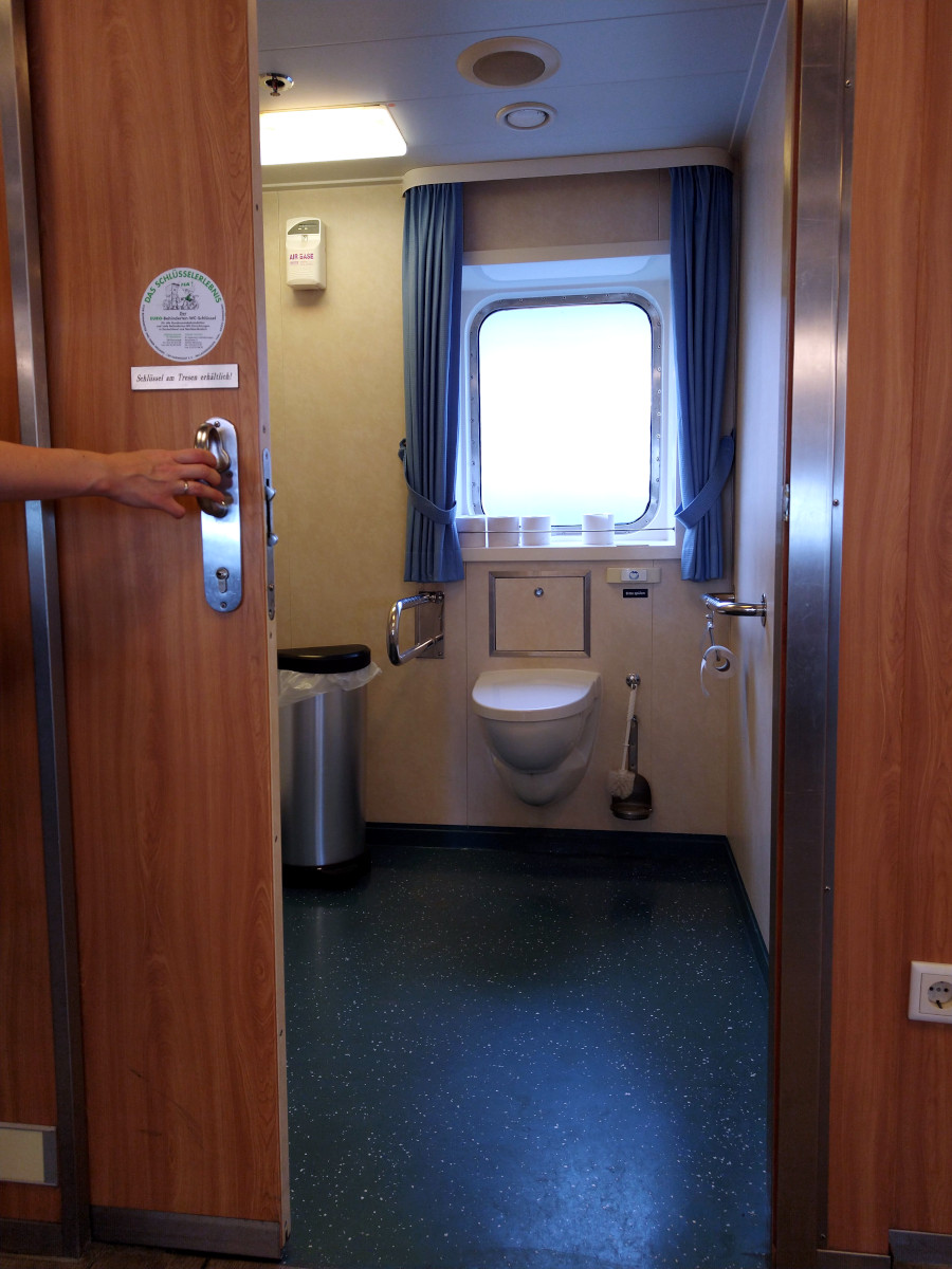 Eine Behinderten-Toilette mit Klapp-Griff links und festem Griff an der rechten Wand.