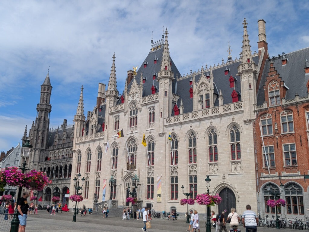 Zweistöckiges gemauertes Gebäude mit zentralen Stufen zur Eingangstür, rechts, links und mittig insgesamt vier schmale Türmchen, das gesamte Gebäude verziert mit kleinen kunstvollen Steinornamenten.